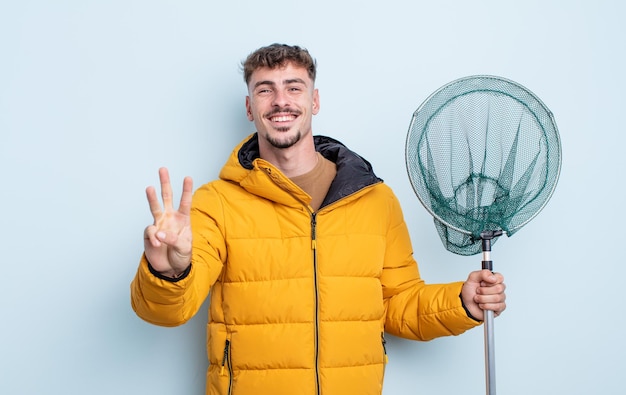 Young handsome man smiling and looking friendly, showing number three. fisherman concept