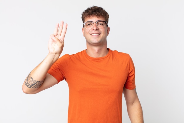 Young handsome man smiling and looking friendly, showing number three or third with hand forward, counting down