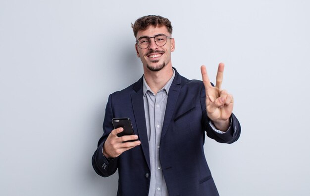 Young handsome man smiling and looking friendly, showing number two. business concept