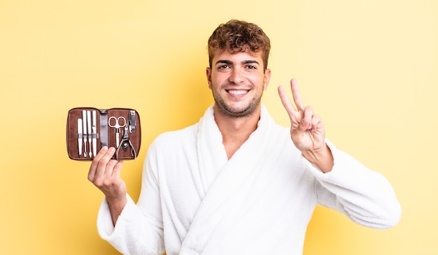 Young handsome man smiling and looking friendly, showing number two. nails tools case concept