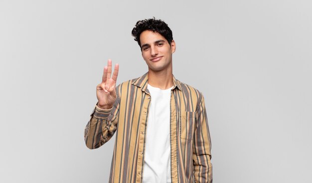 Young handsome man smiling and looking friendly, showing number two or second with hand forward, counting down