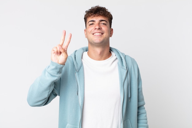 Young handsome man smiling and looking friendly, showing number two or second with hand forward, counting down