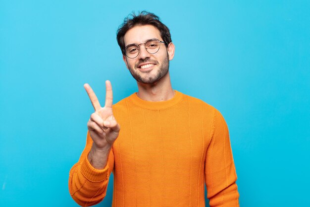 젊고 잘생긴 남자는 웃고 친절하게 보이며 손으로 2번 또는 2번을 앞으로 보여주며 카운트다운