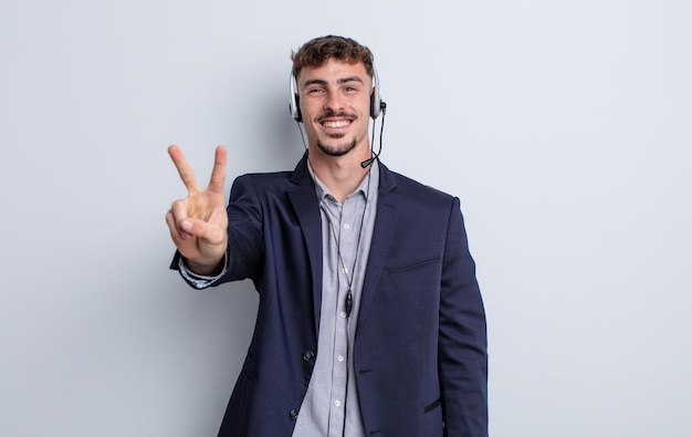 Young handsome man smiling and looking friendly, showing number two. telemarketer concept