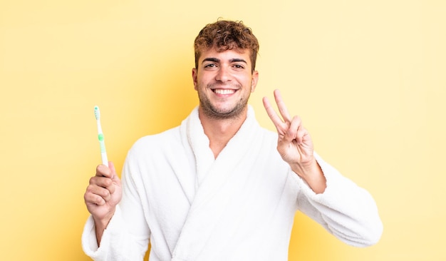 Young handsome man smiling and looking friendly, showing number two. toothbrush concept