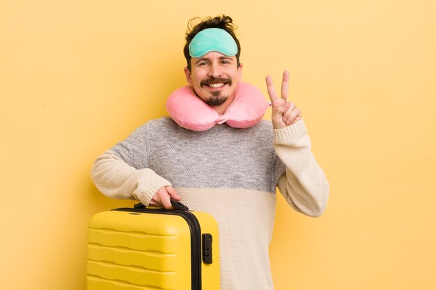 Young handsome man smiling and looking friendly showing number two travel passenger concept