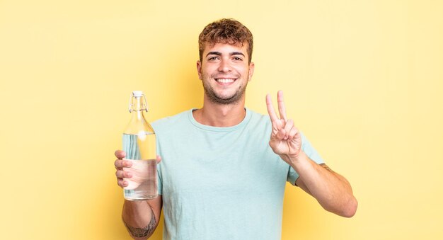 Young handsome man smiling and looking friendly, showing number two. water concept