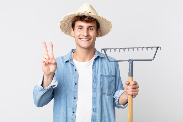 Young handsome man smiling and looking happy, gesturing victory or peace. farmer concept