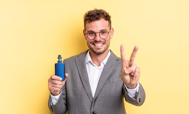 Young handsome man smiling and looking happy, gesturing victory or peace. vaporizer concept