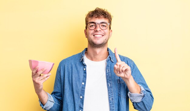 Young handsome man smiling proudly and confidently making number one. empty bowl concept