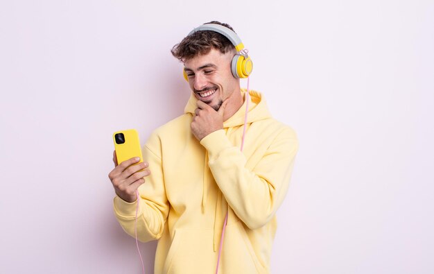 Young handsome man smiling with a happy, confident expression with hand on chin. music concept