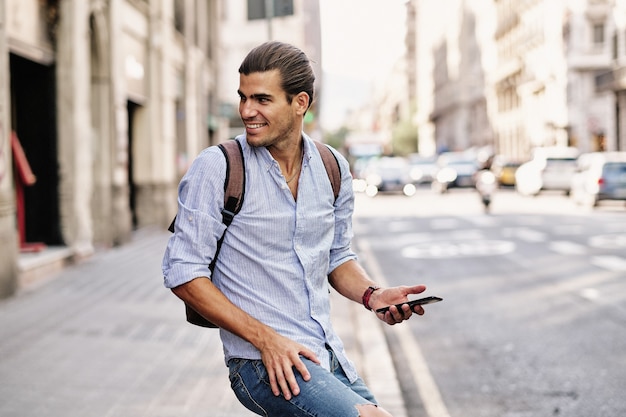 Young handsome man smiling with smartphone at via laietana in Barcelona