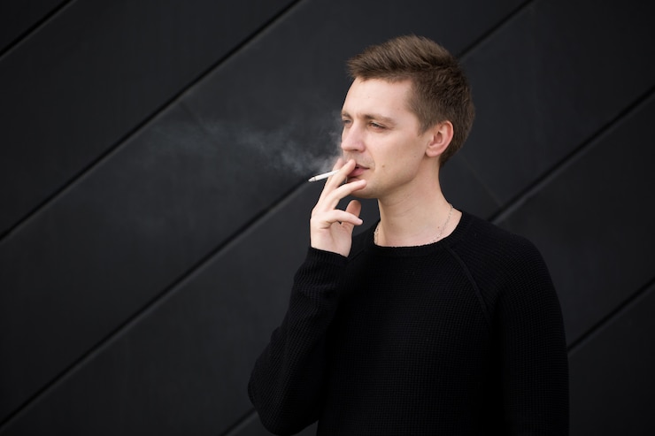 Photo young handsome man smoking a cigarette