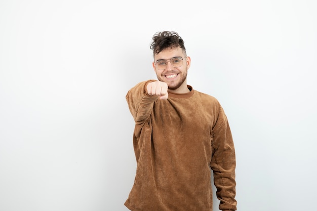 young handsome man standing and feeling happy over white wall. 