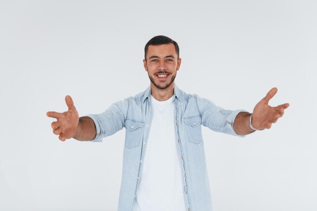 Young handsome man standing indoors against white background