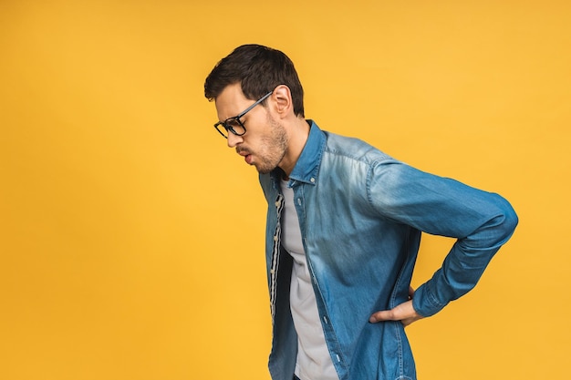 Young handsome man suffering of backache touching back with hand muscular pain