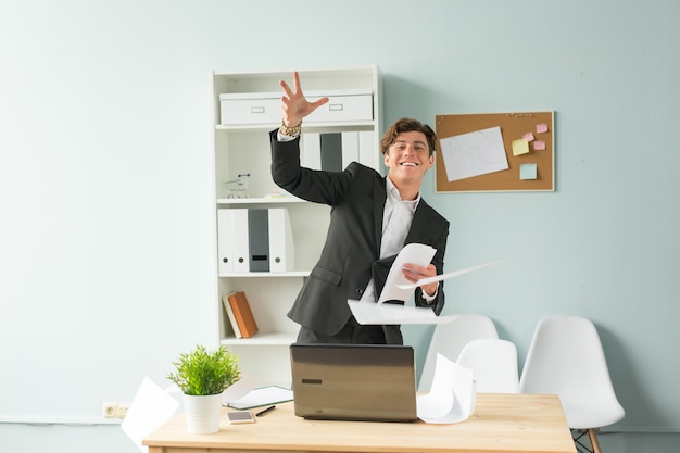 Giovane uomo bello in vestito che si diverte in ufficio