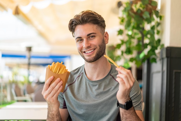 Young handsome man taking fried chips with happy expression