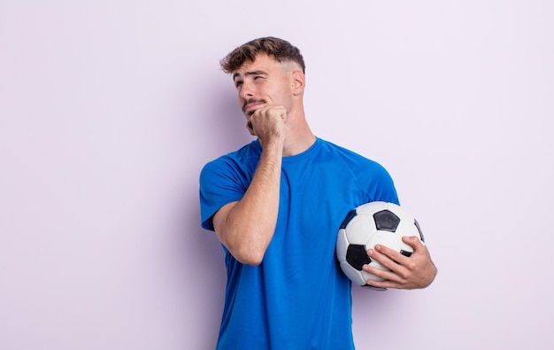 Young handsome man thinking, feeling doubtful and confused. soccer concept