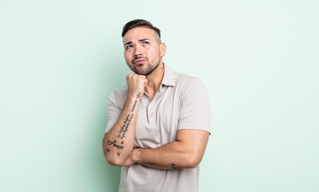 Young handsome man thinking feeling doubtful and confused with different options wondering which decision to make