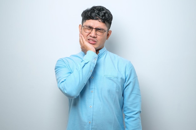 Young handsome man touching mouth with hand with painful expression because of toothache or dental illness on teeth