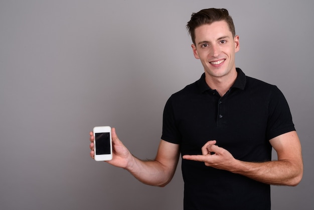 young handsome man using mobile phone on gray