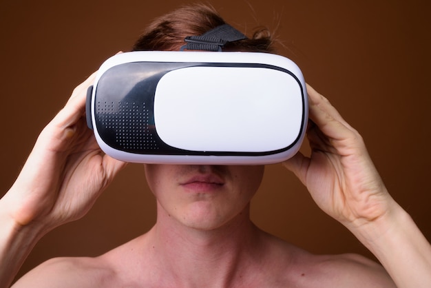 young handsome man using virtual reality glasses shirtless 