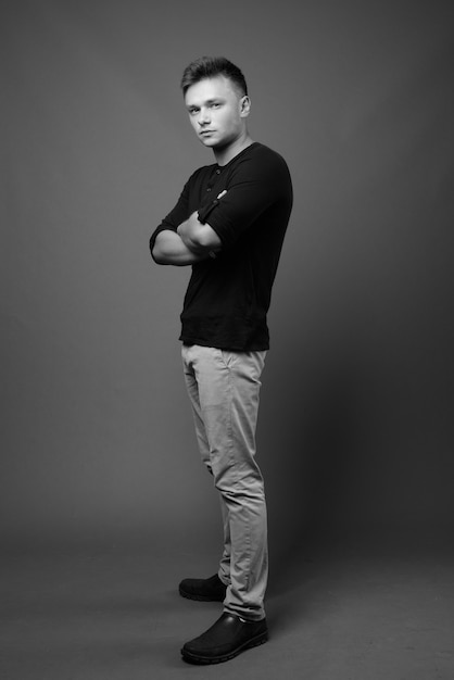 young handsome man wearing black shirt against gray wall. black and white