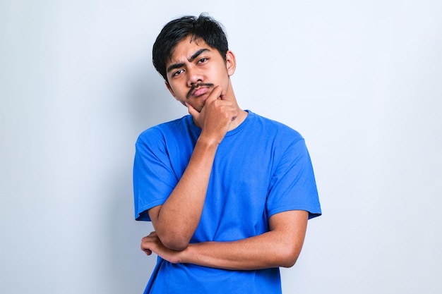 Young handsome man wearing casual shirt standing over white background Thinking worried about a question, concerned and nervous with hand on chin