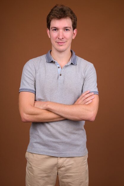 Young handsome man wearing gray shirt on brown