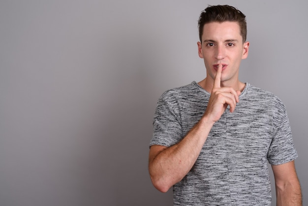 young handsome man wearing gray shirt on gray