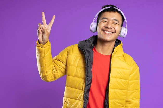 Young handsome man wearing jacket smiling looking to the camera showing two fingers doing victory sign