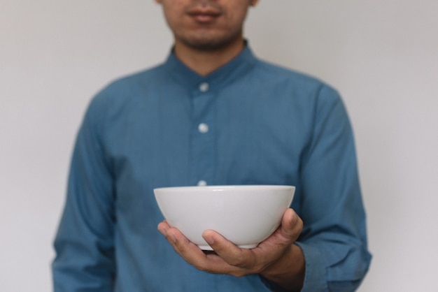 Young handsome man wearing light blue shirt holding warm cup of breakfast.