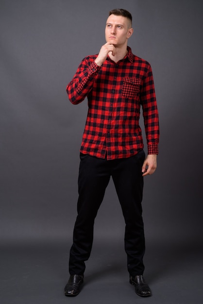 young handsome man wearing red checkered shirt on gray