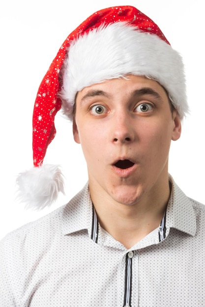 Young handsome man wearing a Santa hat over white background surprised showing and pointing something that is on her hand