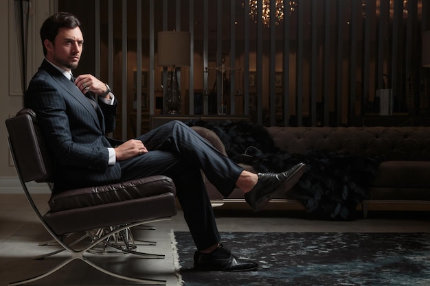 Young handsome man wearing suit and sitting on a chair