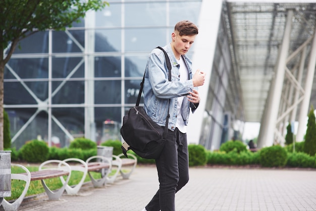 Young handsome man with a bag on his shoulder in a hurry to the airport.