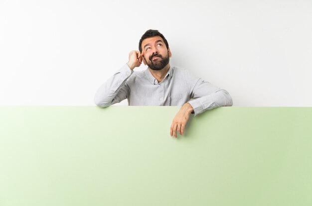 Young handsome man with beard holding a big green empty placard