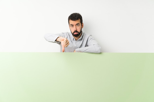 Young handsome man with beard holding a big green empty placard