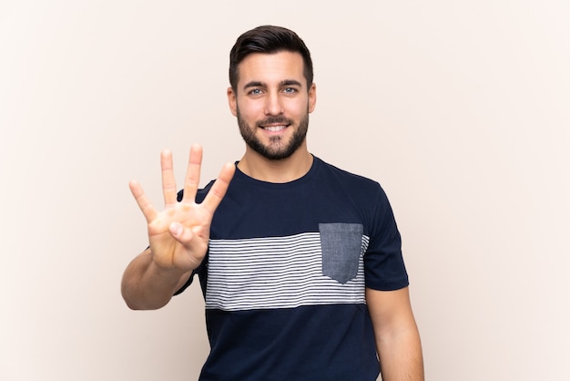 Young handsome man with beard isolated happy and counting four with fingers