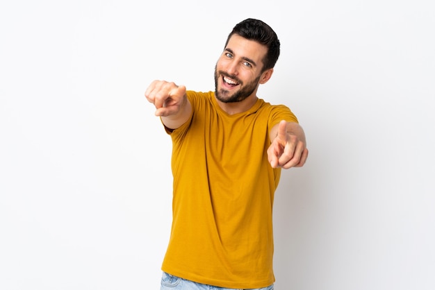 Young handsome man with beard isolated on white pointing front with happy expression