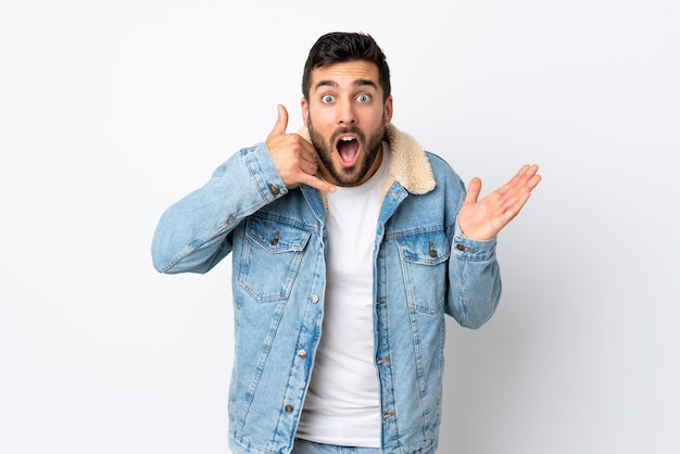 Young handsome man with beard isolated on white wall making phone gesture and doubting