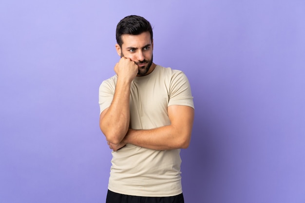 Giovane uomo bello con la barba sopra isolato con espressione stanca e annoiata