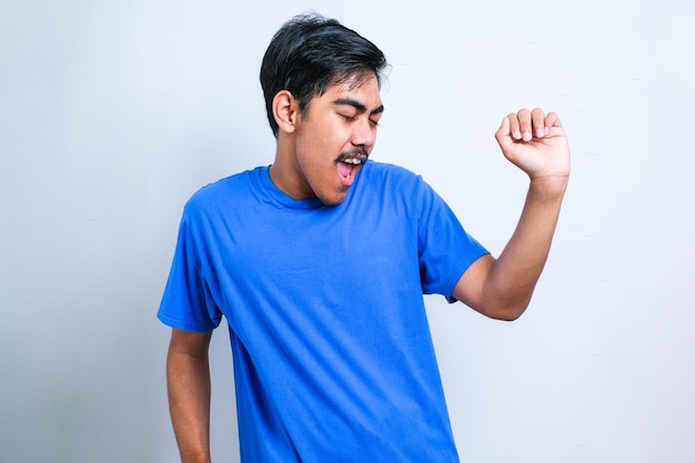 Young handsome man with beard wearing white t-shirt over white background Dancing happy and cheerful, smiling moving casual and confident listening to music