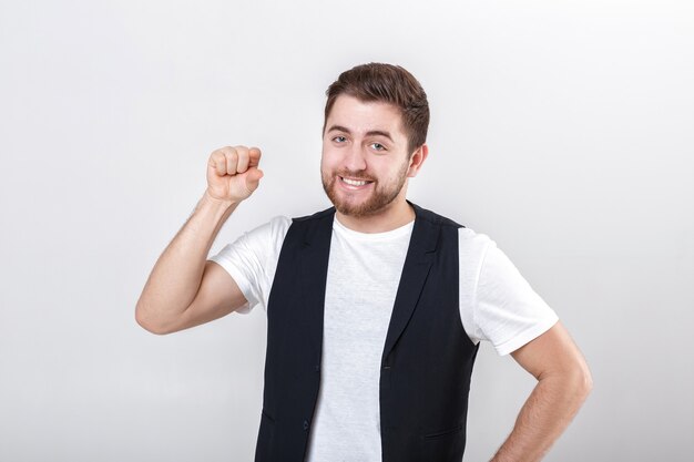 Young handsome man with a beard in a white shirt and a black waistcoat shows the gesture of knocking