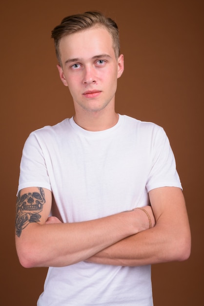 Photo young handsome man with blond hair against brown wall