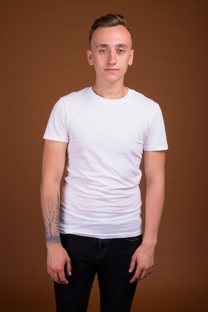 Young handsome man with blond hair against brown wall