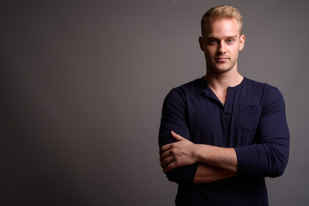 Young handsome man with blond hair against gray