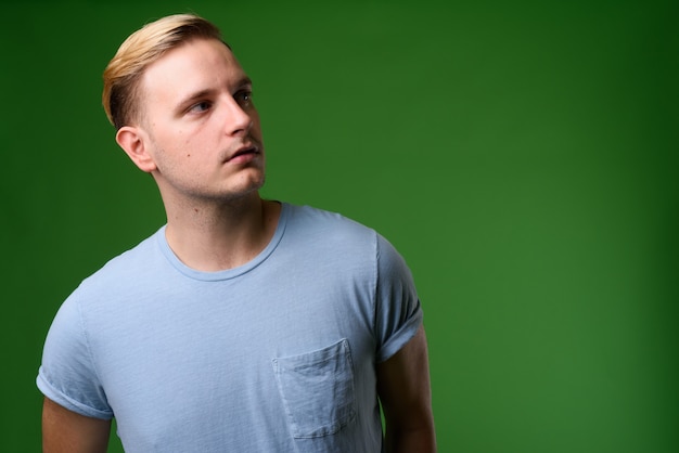 Young handsome man with blond hair against green background