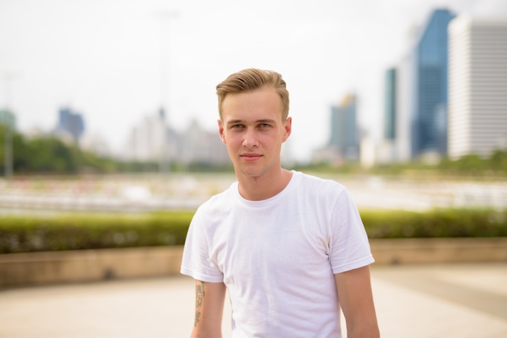 Photo young handsome man with blond hair relaxing at the park